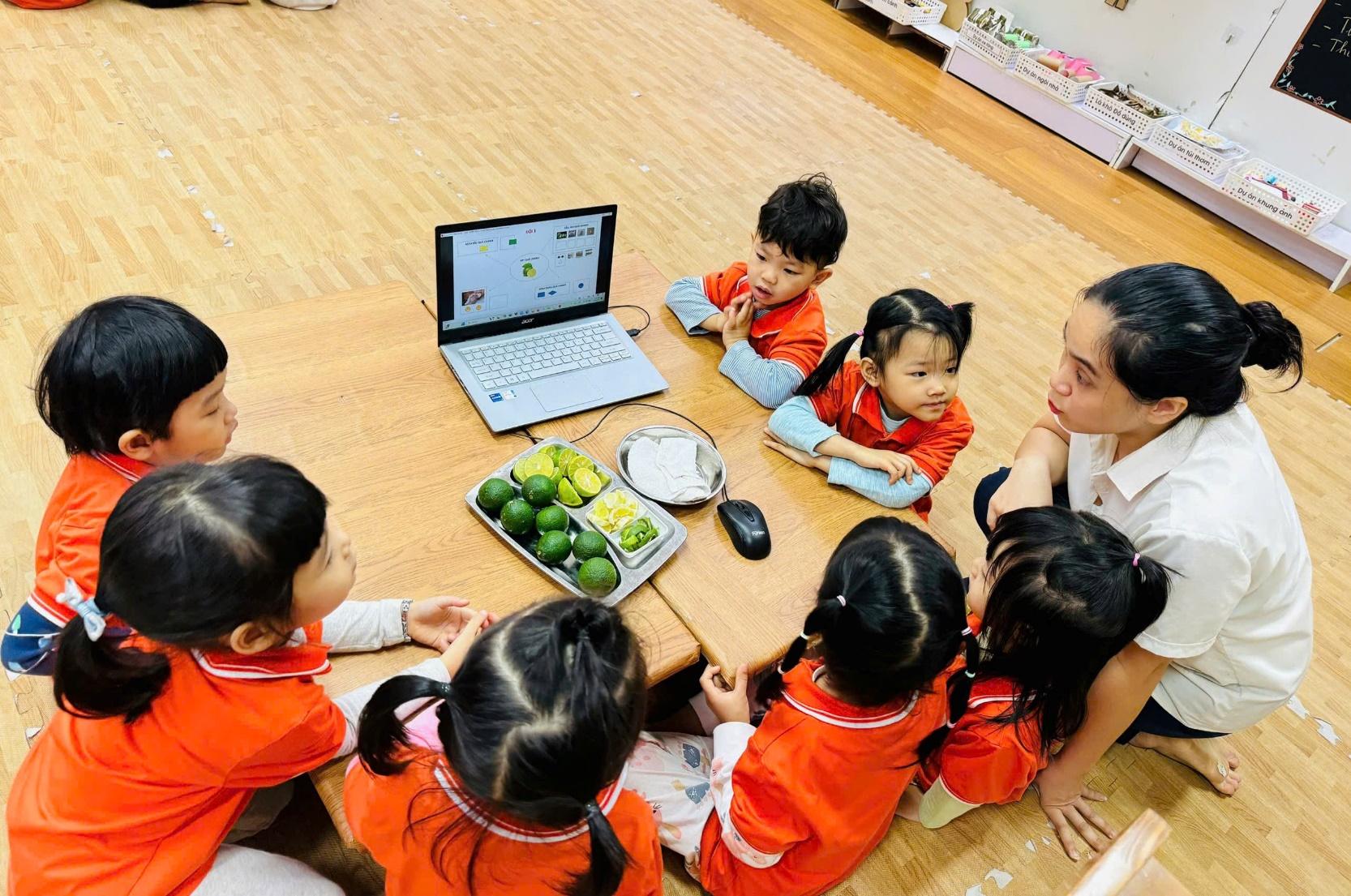 A group of children sitting around a table with a computer

Description automatically generated