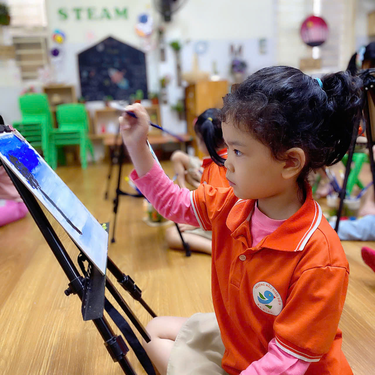 A child painting on a easel

Description automatically generated