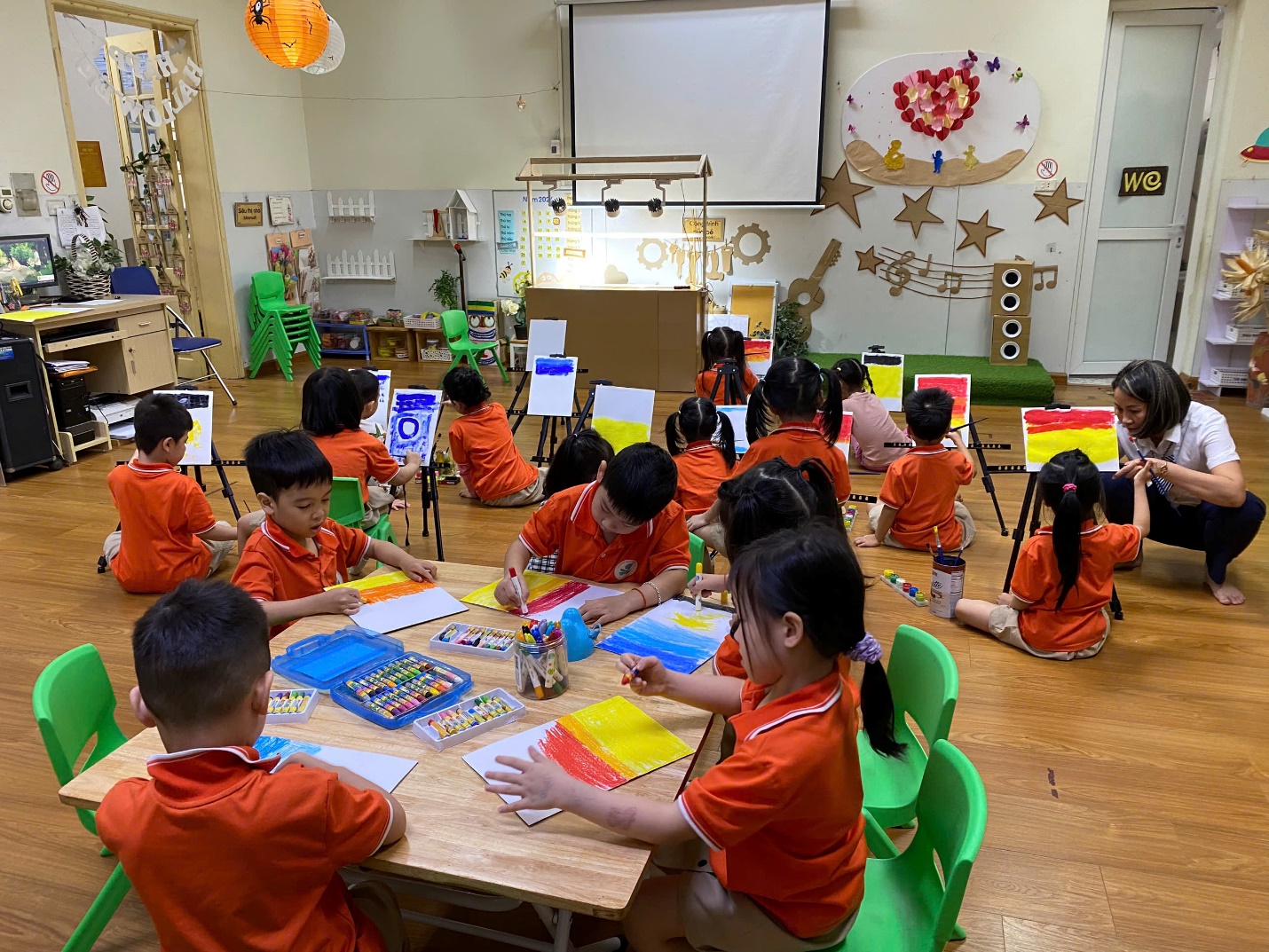 A group of children sitting at a table in a classroom

Description automatically generated